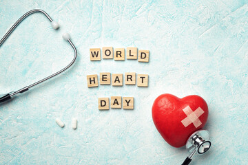 Red heart with doctor stethoscope and the inscription world heart day on blue textured background,...
