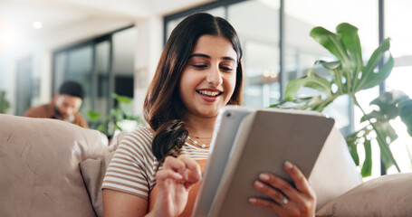 Woman, relax and reading on sofa with tablet, social media and ebook for weekend chill in home. Person, happy or tech in living room for streaming subscription, email notification or download new app