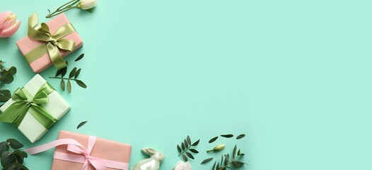 Decorative bunny, gift boxes, flowers and green leaves on turquoise background with space for text....