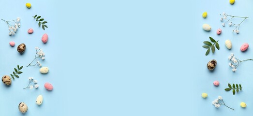 Frame made of flowers, green leaves and Easter eggs on light lue background