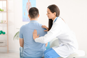 Female doctor checking posture of young man in clinic