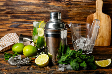 Shaker and ingredients for preparing mojito on wooden background