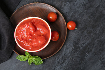 Bowl of canned and fresh tomatoes on dark background