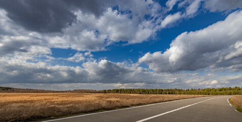A road with a clear blue sky and a few clouds