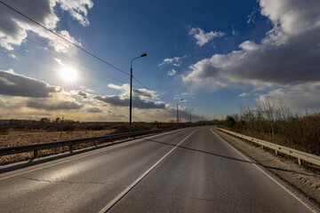 Fototapeta premium A road with a clear blue sky and a sun in the background