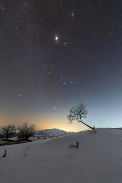Winter constellations and Jupiter over snowy landscape