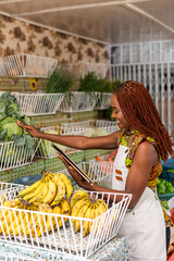 Successful African female business owner of local fresh produce market and grocery store uses a...