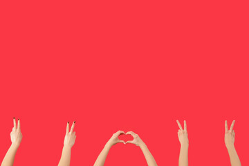 Female hands showing peace and heart gestures on red background