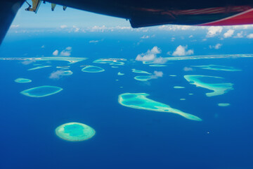 Aerial view of beautiful tropical island among blue sea water at Maldives paradise with boat on background