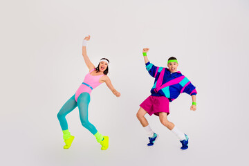 Energetic young couple enjoying a vibrant workout session in retro activewear against a white background