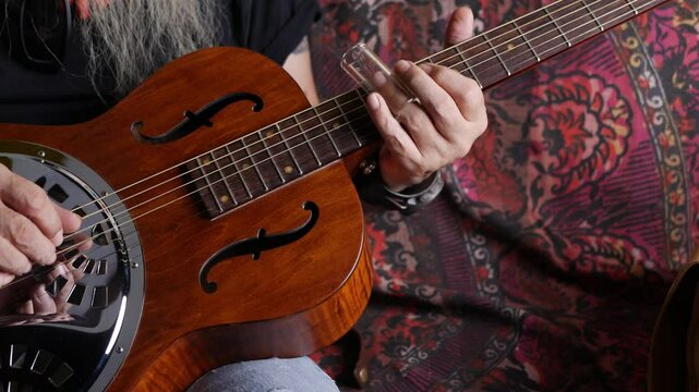 Male musician hand play Vintage Resonator acoustic dobro blues slide guitar.