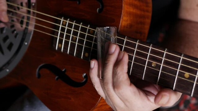 Male musician hand play Vintage Resonator acoustic dobro blues slide guitar.