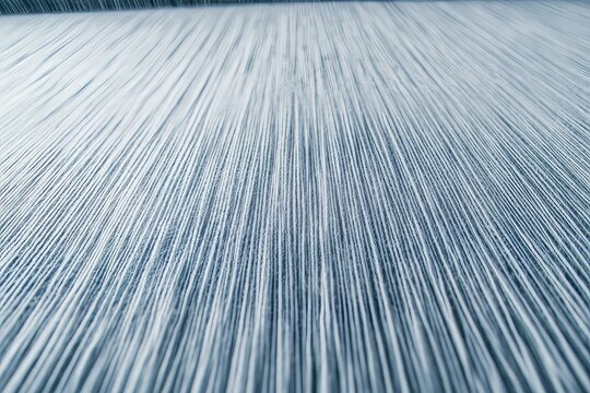Close-up view of parallel threads on a loom, showcasing the intricate details of textile manufacturing.