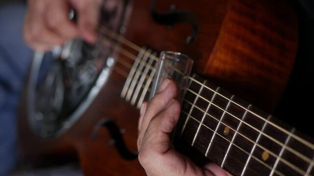 Male musician hand play Vintage Resonator acoustic dobro blues slide guitar.
