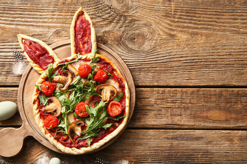 Board with tasty pizza on wooden background. Easter celebration