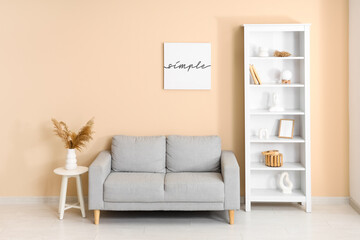 Grey sofa and shelving unit near beige wall in interior of living room