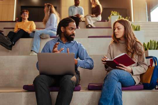 University professor explaining lesson to student with laptop
