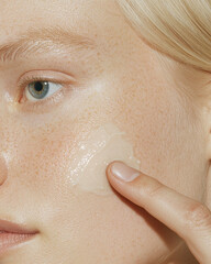 Fototapeta premium Close-up shot of a light skin Caucasian woman applying cream on face