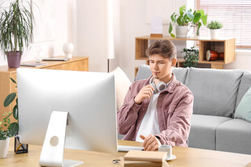 Thoughtful male student with computer studying online at home