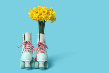 Vintage roller skates with bouquet of beautiful narcissus flowers on blue background