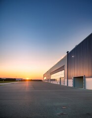 Fototapeta premium Modern Industrial Warehouse at Sunset with Clear Sky