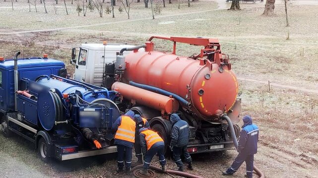 Sewer cleaning workers clean sewers with a vacuum hose and special equipment. Specialized sewer maintenance vehicles, industry