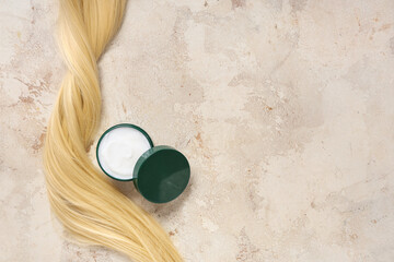 Blonde strand with jar of hair mask on beige grunge background