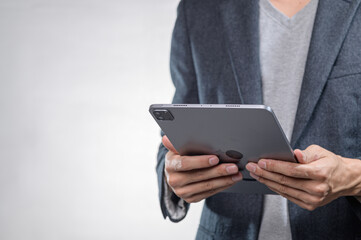Hands Holding Modern Tablet in Professional Attire Against Neutral Background