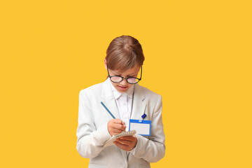 Portrait of teenage journalist writing in notebook on yellow background