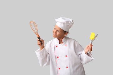 Naklejka premium Portrait of teenage chef with utensils on grey background