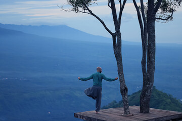 Naklejka premium A man meditates and does yoga from the back