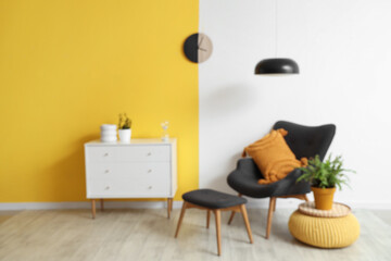 Interior of stylish living room with black armchair, chest of drawers, lamp and clock on yellow...