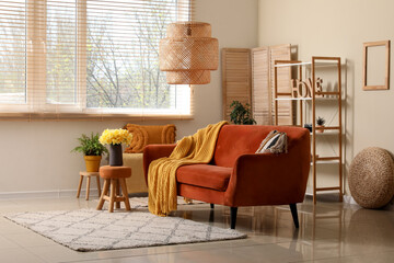 Comfortable sofa with plaid and  beautiful daffodils in living room