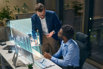 Two Professionals Discuss Analytics Displayed On A Futuristic Digital Interface In Office...