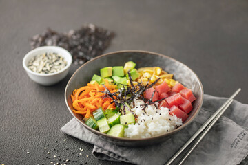 A traditional dish of Hawaiian cuisine. Poke bowl with tuna and vegetables in a bowl on the table