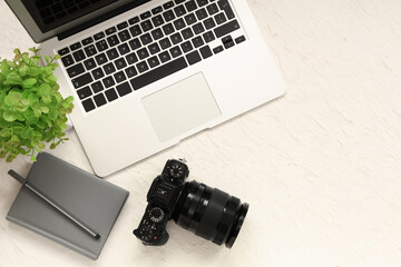 Professional photo camera, modern laptop and notebook on light background
