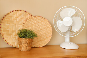 Modern electric fan with decor on commode at home