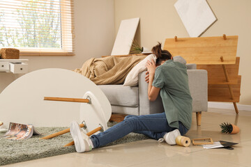 Young woman hiding near sofa during earthquake at home