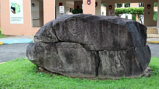 Large ancient stone with Taino Symbols carves sits in grassy area