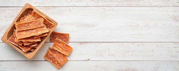 Delicious jerky dog treats in wooden bowl on rustic wooden surface, perfect for rewarding your furry friend with tasty snack