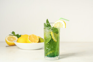 Glass of lemonade with lemons and mint on white background