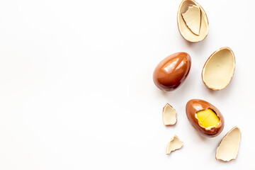 Broken and whole chocolate egg on white background, top view. Chocolate background