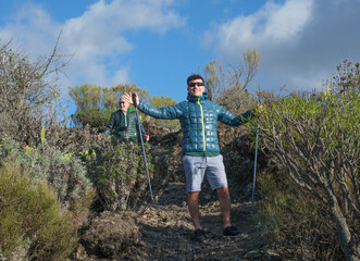 Multigenerational family couple enjoying outdoors excursion, grandfather and adult grandson hiking...