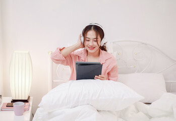 Beautiful young woman playing with digital tablet on bed