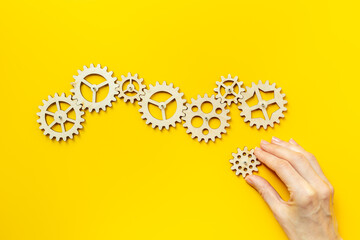 Hand is adding a cog wheel to a chain of gears. Idea or solution concept