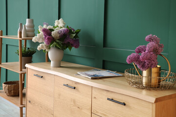 Stylish wooden cabinet and shelving unit near green wall in room