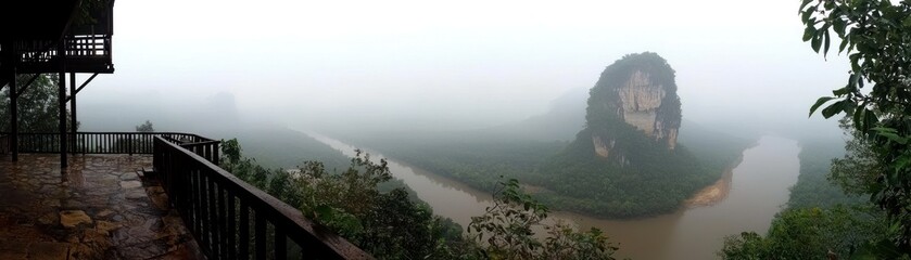A misty panoramic view of a river and mountain landscape