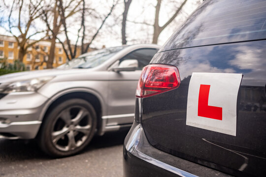 UK- Learner driver L plates attached to car on urban road in the UK