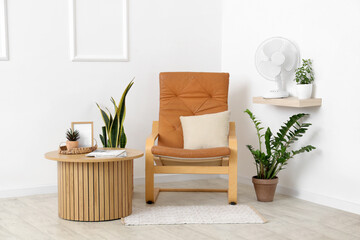 Electric fan and houseplants on shelf at home