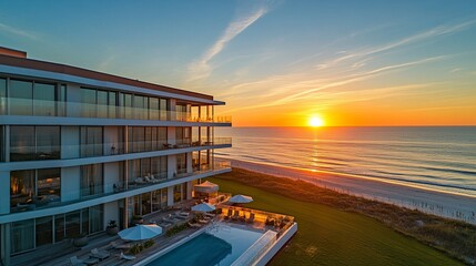 Fototapeta premium Sleek oceanfront condo featuring floor-to-ceiling glass windows, a large balcony with panoramic ocean views, vibrant sunset tones lighting the scene, tranquil coastal elegance. 